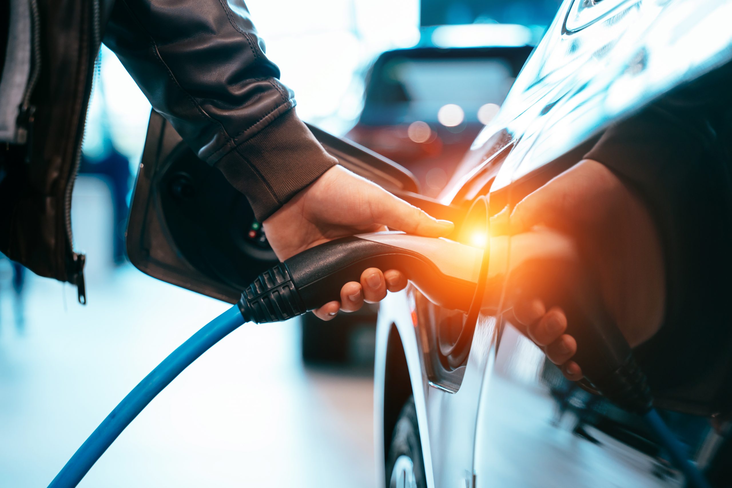 A man's hand plugging in an electric car for charging