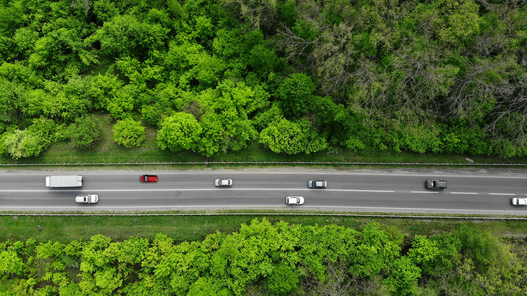 top-down aerial drone view of a road in a natural setting with traffic